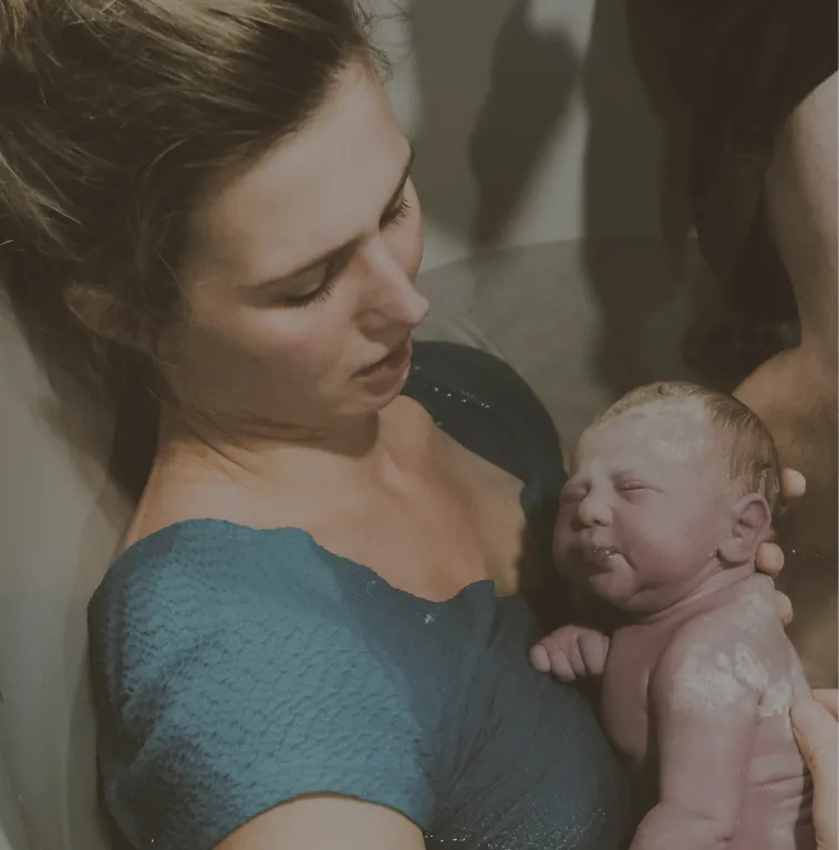 Mother holding her newborn in a birthing tub after delivery